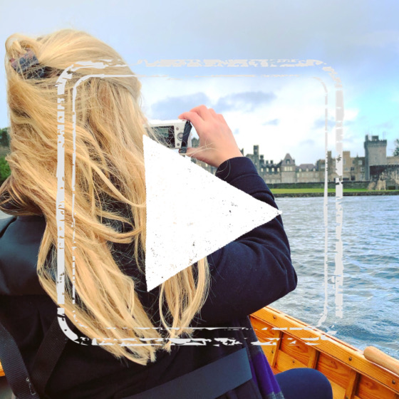 Female in a boat photographs ashford castle in Ireland.
