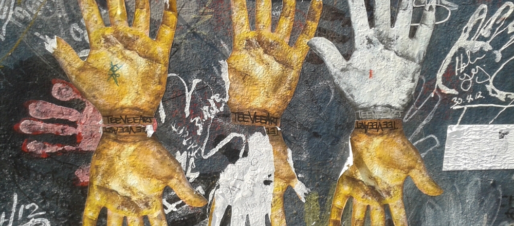 Berlin street art with gold and white hands.