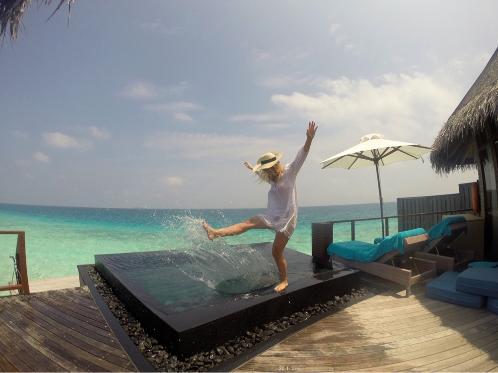 A blonde female splashes around in an over water bungalow in the Maldives.