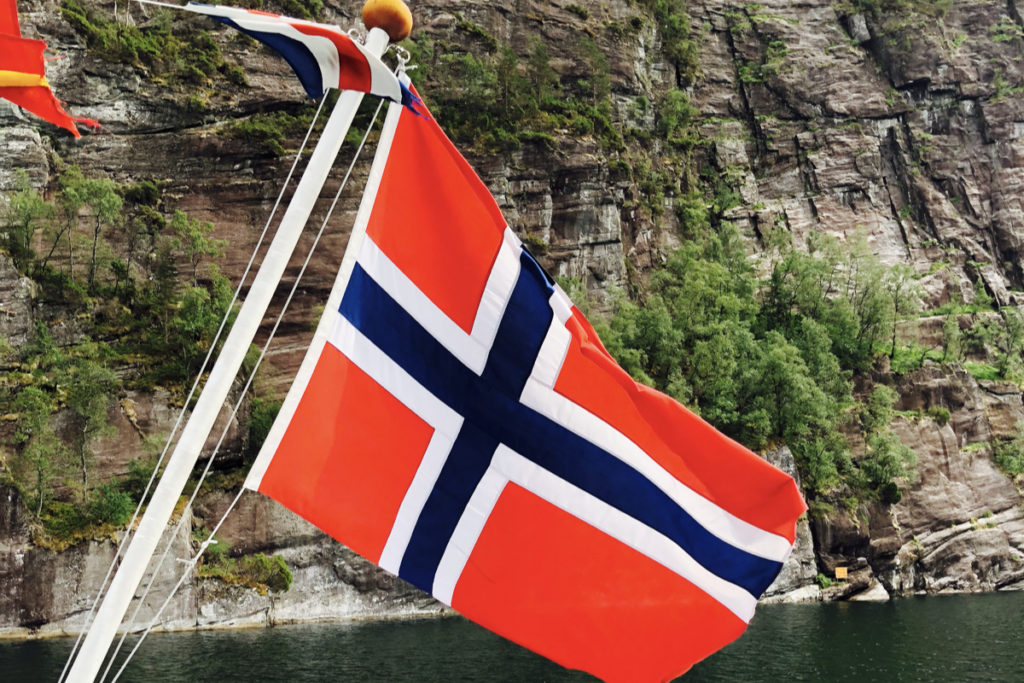 The Norwegian flag billows in the wind on a fjord tour.