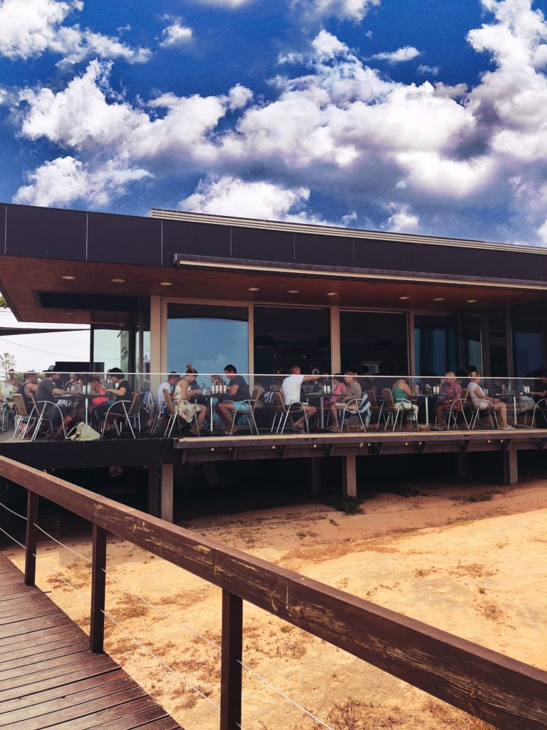 Beach goers eat outside of the seafood restaurant, O Camilo.